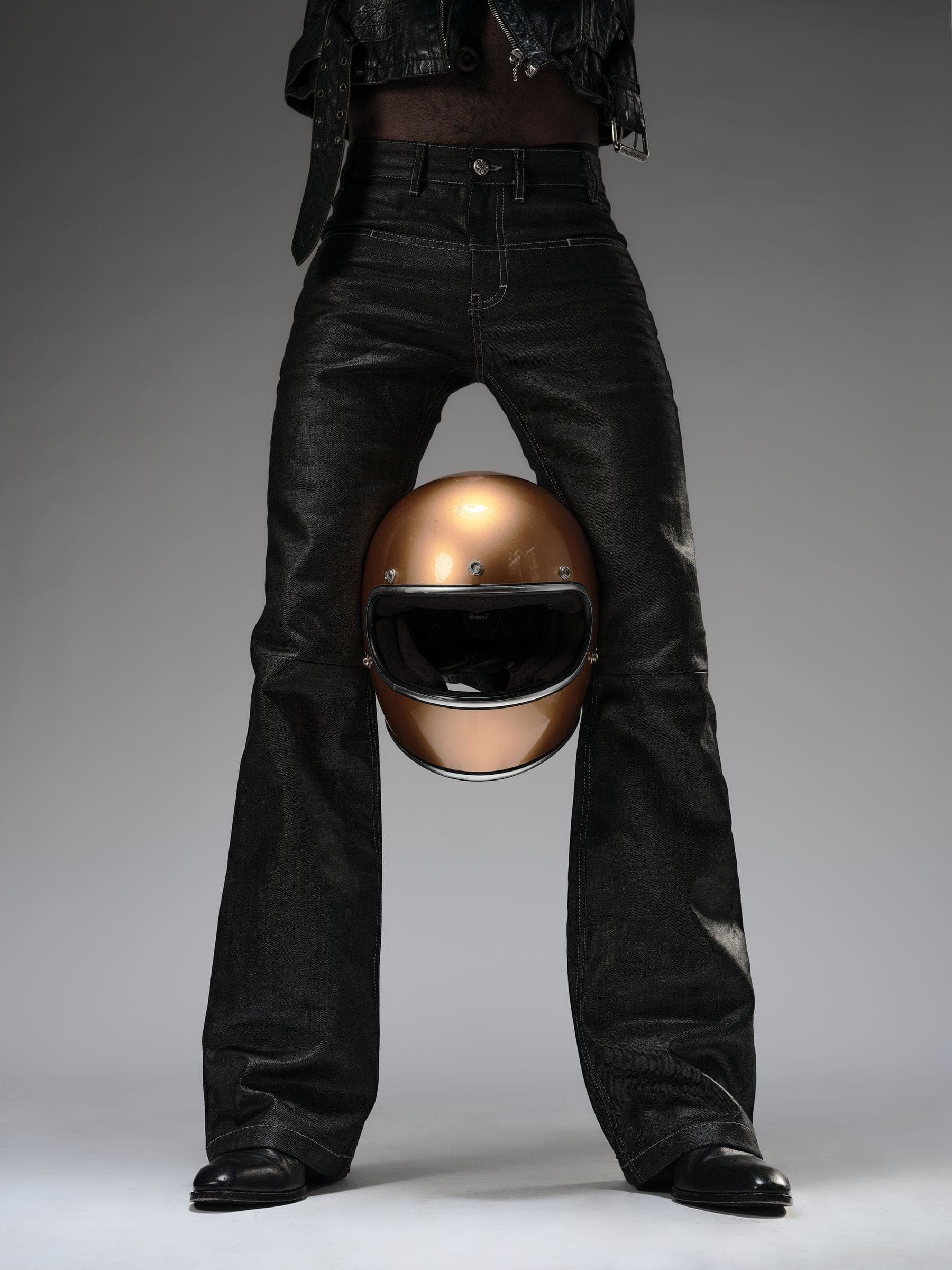 From the CLOSNEA: TYPE campaign: the TYPE Denim Bootcut and Chelsea boots, a copper helmet held between the knees.